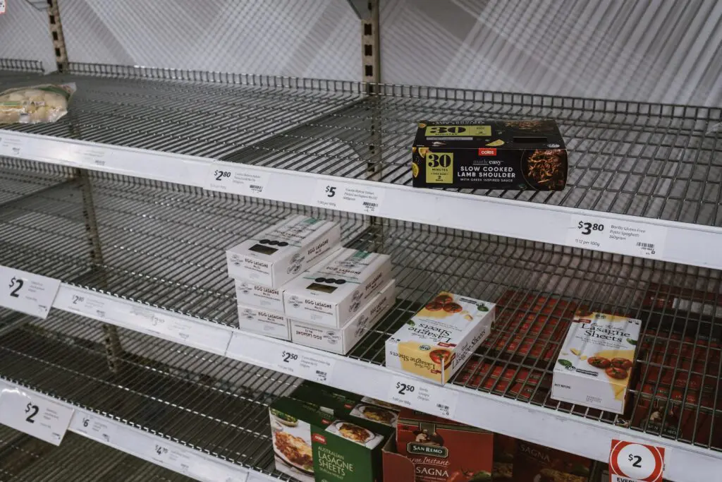 Grocery store shelves that are almost empty except for a few remaining boxes of pasta