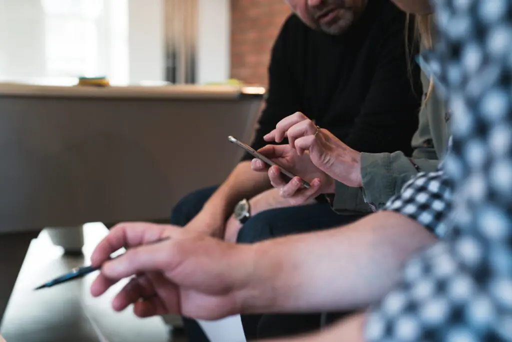 Several people sitting in a row looking at an iPhone and taking notes