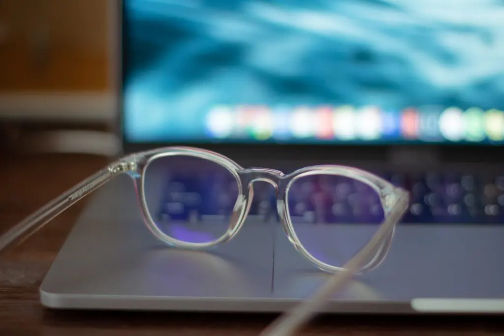Glasses with clear frames sitting on the edge of a laptop