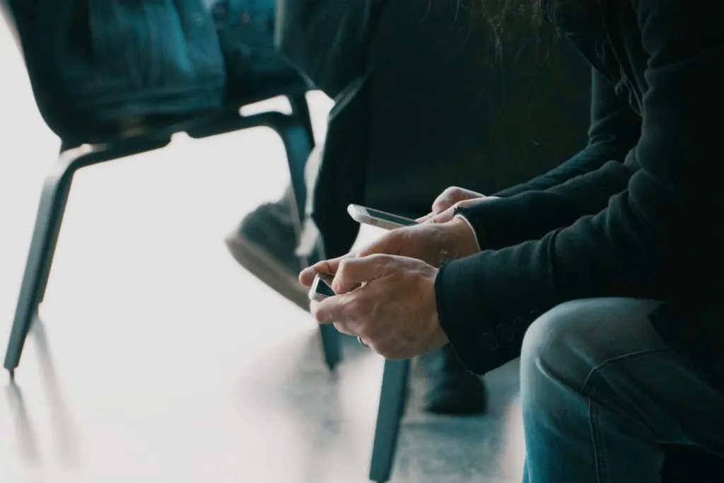 Several people sitting in chairs looking at their phones