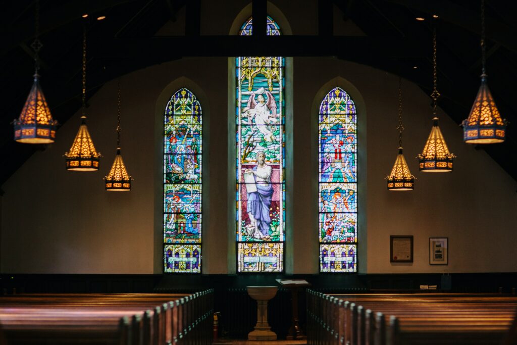 A photo inside an empty church with beautiful stained glass windows