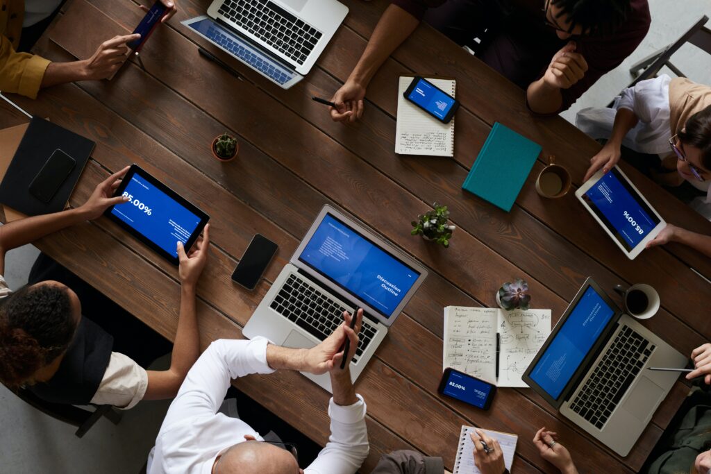 A group sits around a conference table with laptops and tablets 